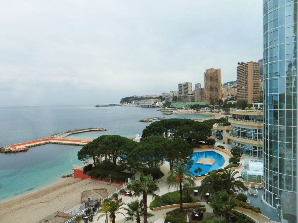 View of Monaco's coastline featuring luxury hotels, beach, and city skyline.