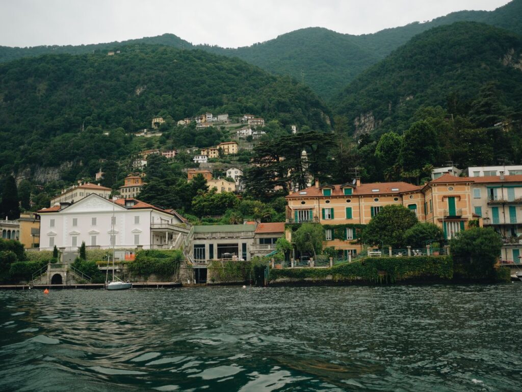 Picturesque waterfront with colorful villas at Lake Como, Italy, featuring lush mountains and serene waters.
